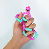 Hand holding a pink and teal flamingo Tangle Jr. Pet fidget toy in a loose grip