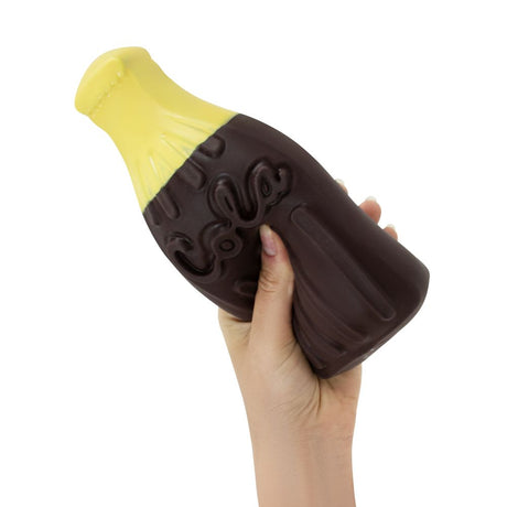 Hand squeezing The Big Squij giant cola bottle squishy with yellow top and brown body