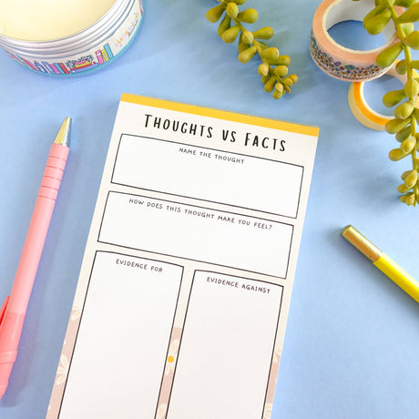 Thoughts vs Facts CBT notepad flat lay on blue, mental health stationery