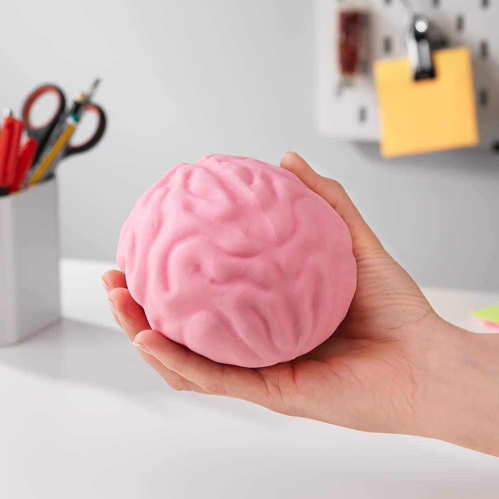 Pink brain-shaped stress ball held in a hand with a blurred office background